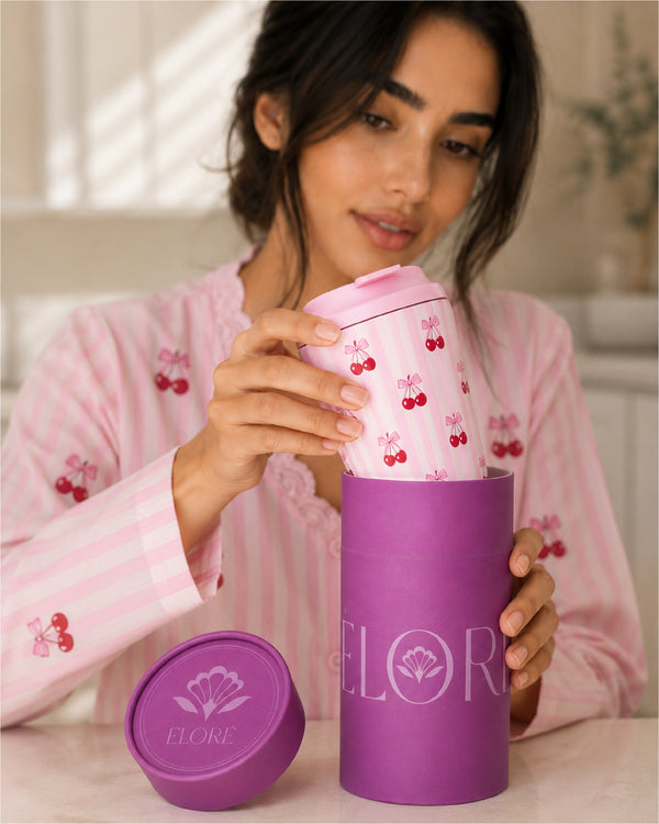 Woman in pink pajamas holding a purple container with 'Elorè' branding
