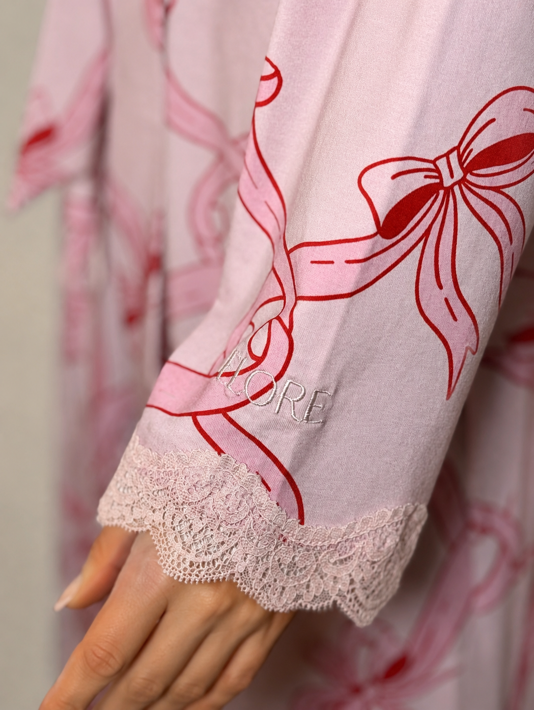 Close-up of a pink garment with red floral patterns and lace trim.