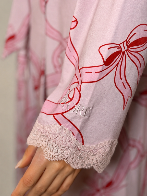Close-up of a pink garment with red floral patterns and lace trim.